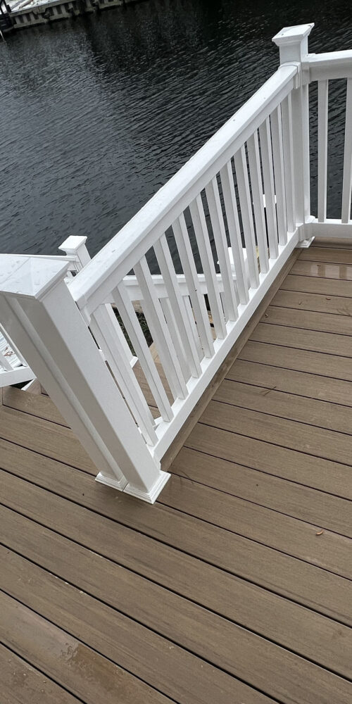 Professional deck resurfacing in North Carolina using TimberTech PVC boards in a gray finish with high-contrast white railings and a picture-frame border.