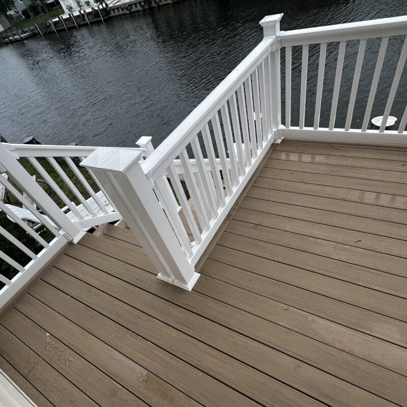 Professional deck resurfacing in North Carolina using TimberTech PVC boards in a gray finish with high-contrast white railings and a picture-frame border.