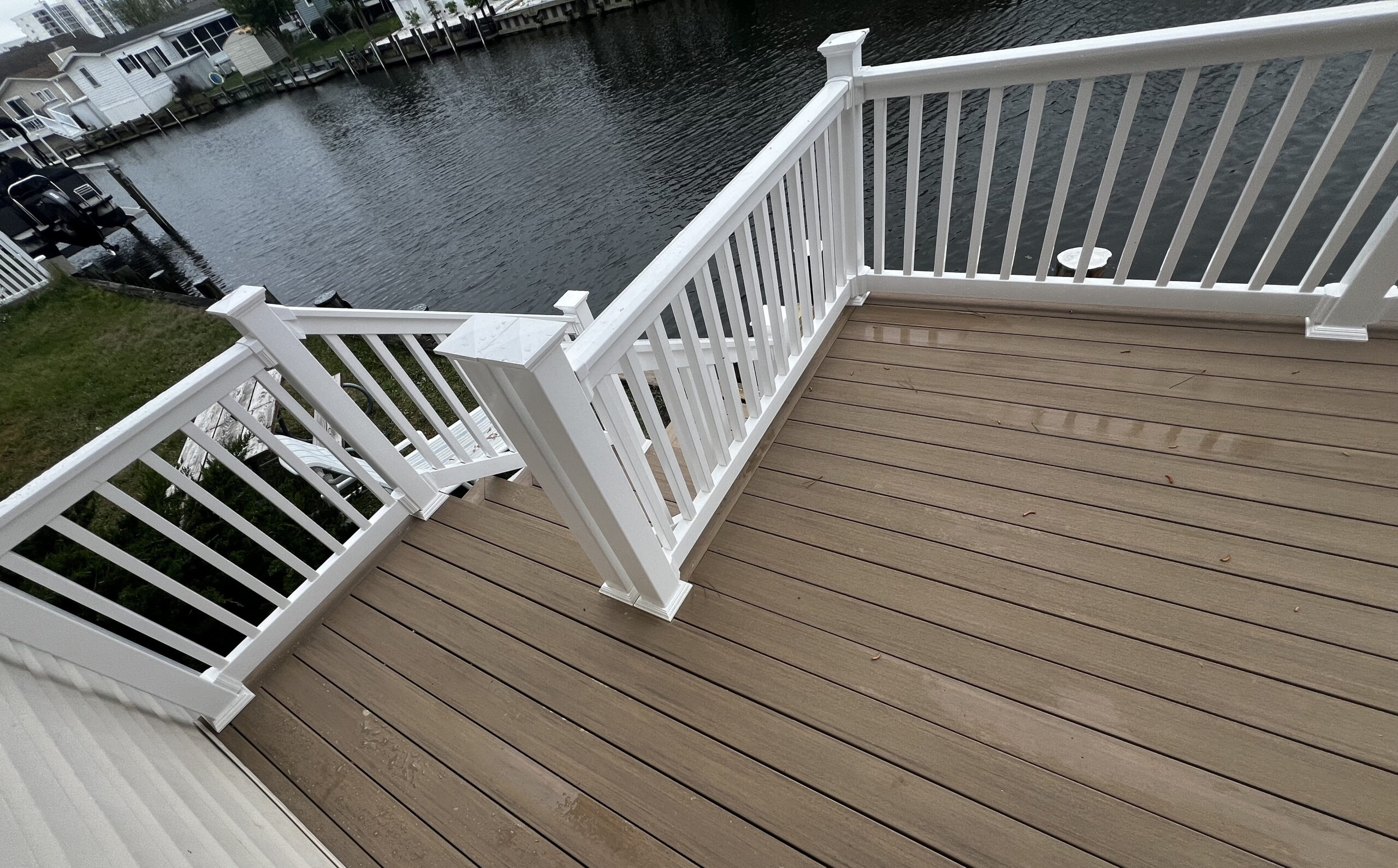 Professional deck resurfacing in North Carolina using TimberTech PVC boards in a gray finish with high-contrast white railings and a picture-frame border.