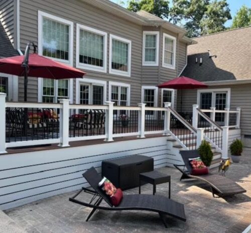 POV of a furnished Azek PVC deck with white railings, featuring a patio table and outdoor chairs in a North Carolina backyard.
