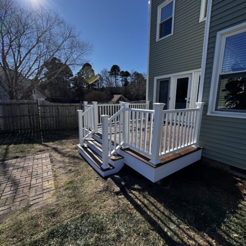 POV view of a custom Trex composite deck with white vinyl railings and stairs, leading to the back entrance of a home in Garner, NC