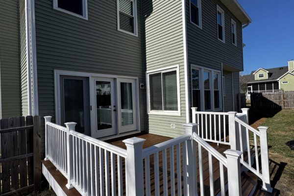 POV view of a custom-built Trex composite deck with white railings and stairs leading to a back door in Garner, NC.
