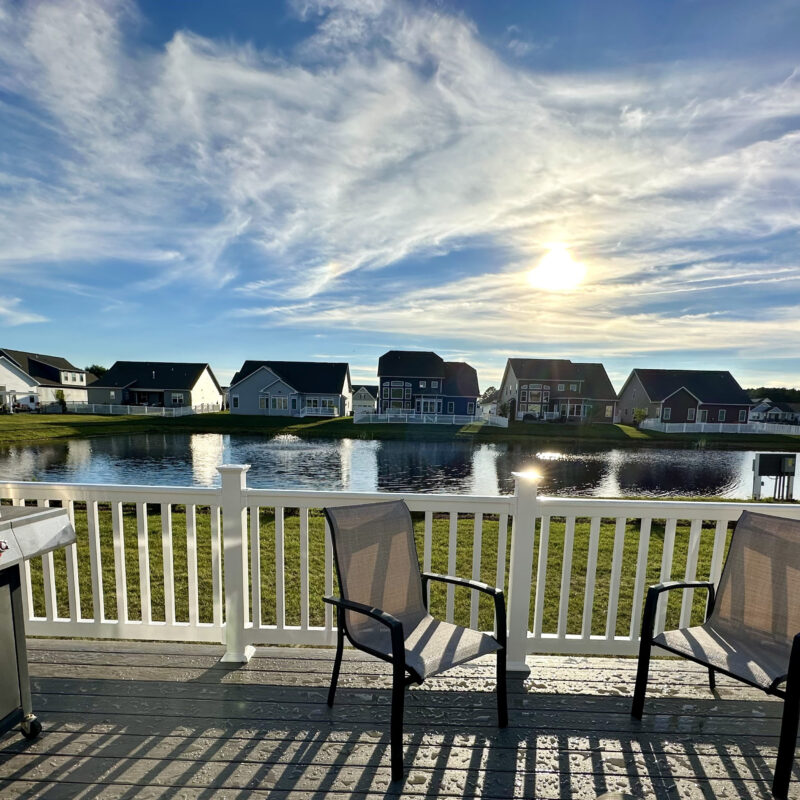 Elevated Trex composite deck with white railings and a stainless steel grill overlooking a North Carolina residential neighborhood.