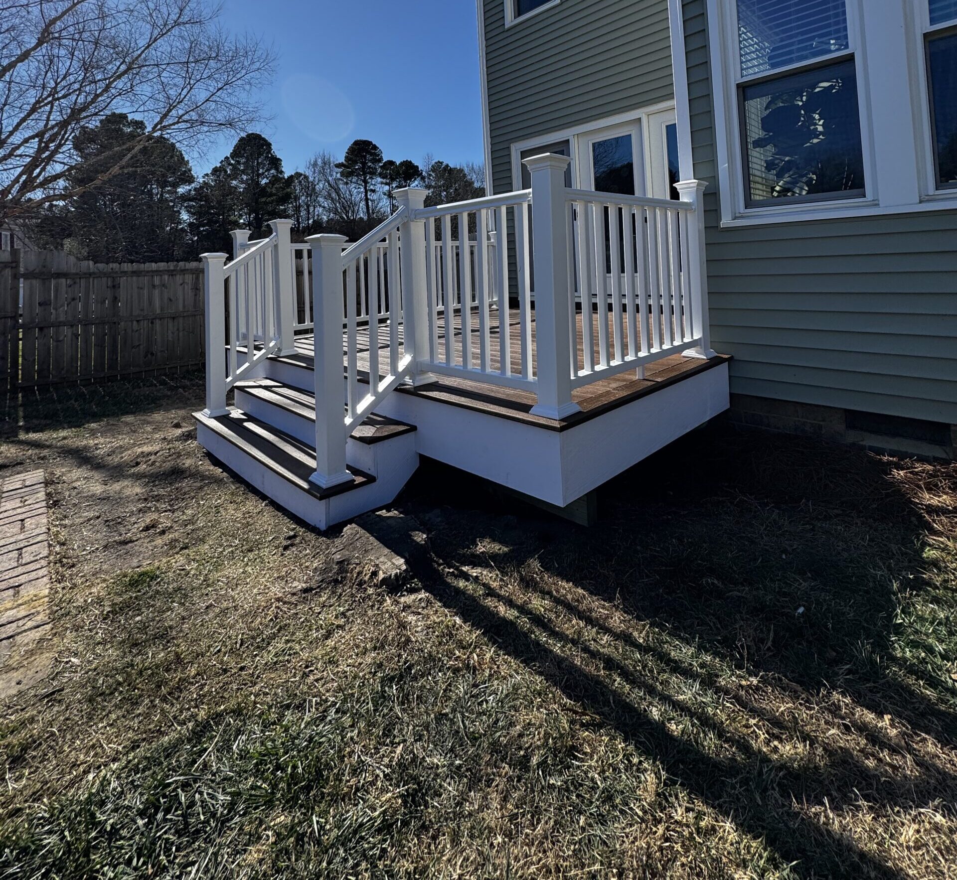 Completed custom composite deck in Fuquay-Varina, NC, featuring white railings and wide stairs by Titan Decks.