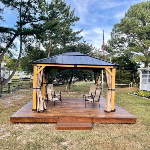 Wood-Deck-with-Pergola-North-Carolina Custom wood deck with a black metal roof pergola and outdoor seating area in North Carolina by Titan Decks.