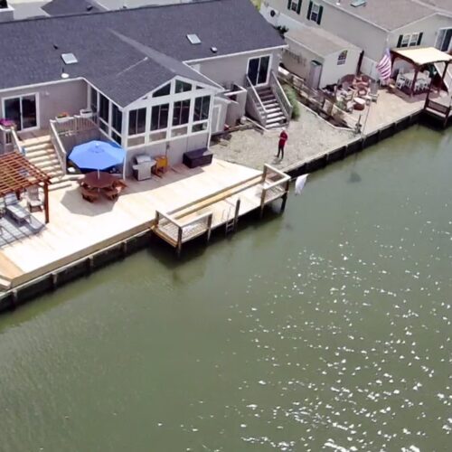 Waterfront-Wood-Deck-Pergola-Dock-NC Aerial view of a completed waterfront wood deck, pergola, and boat dock system in North Carolina by Titan Decks.