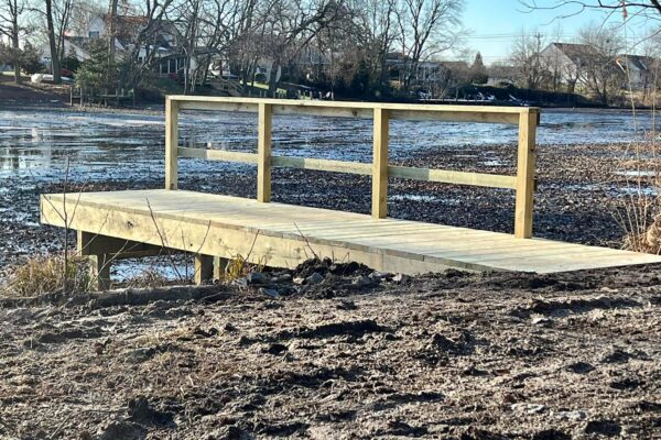 Completed custom wood dock and deck with safety railings on a North Carolina waterfront by Titan Decks.