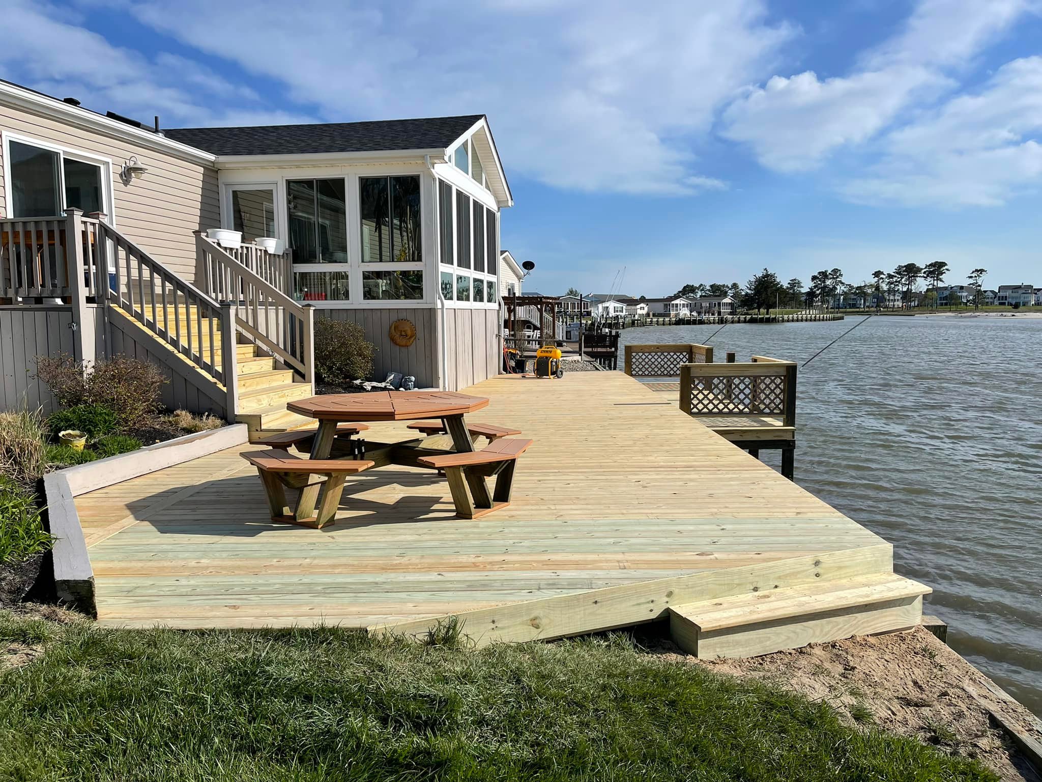 Completed wide wood deck and dock area with a picnic table on a North Carolina waterfront by Titan Decks.