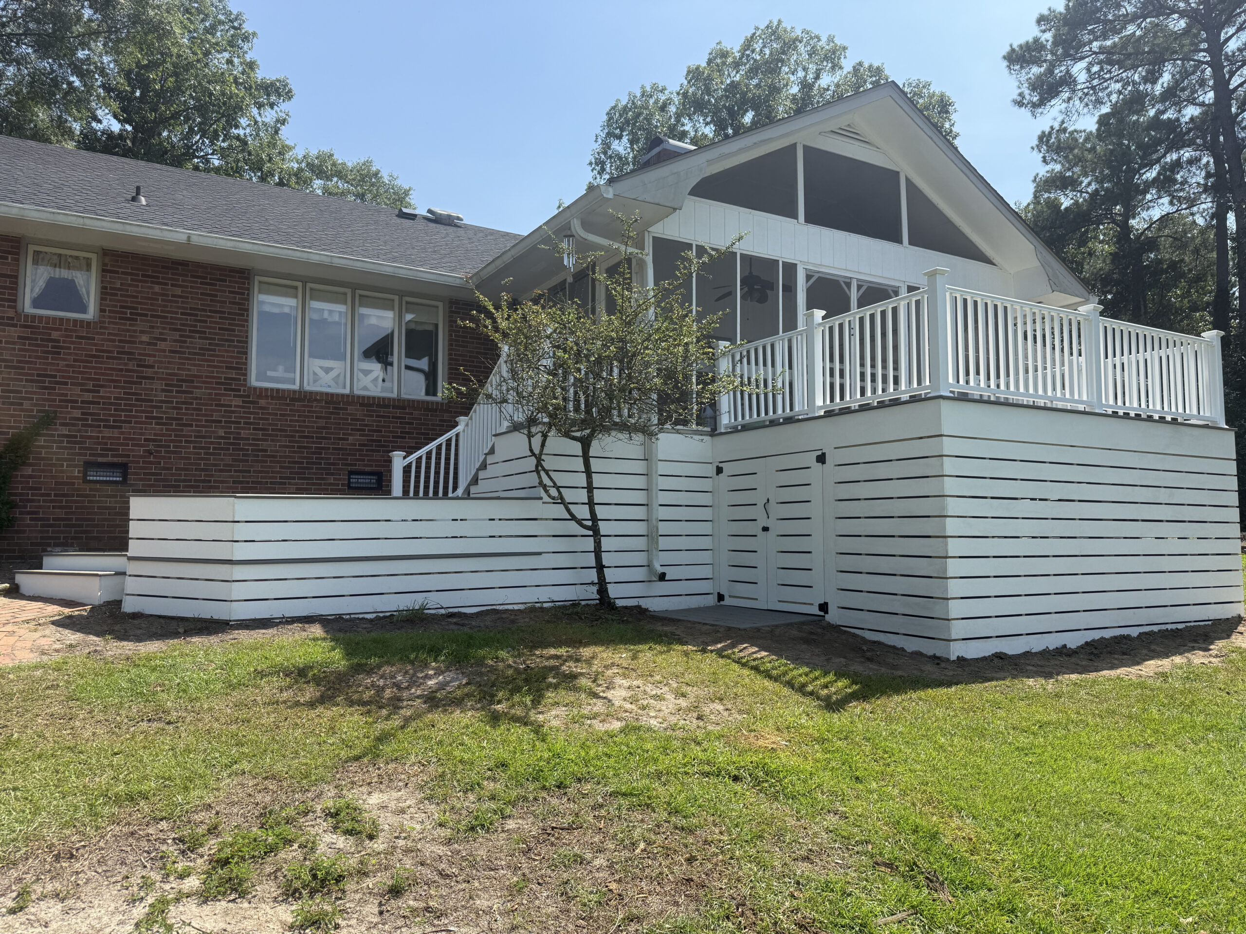 Resurfaced deck with white horizontal skirting on a brick home in North Carolina