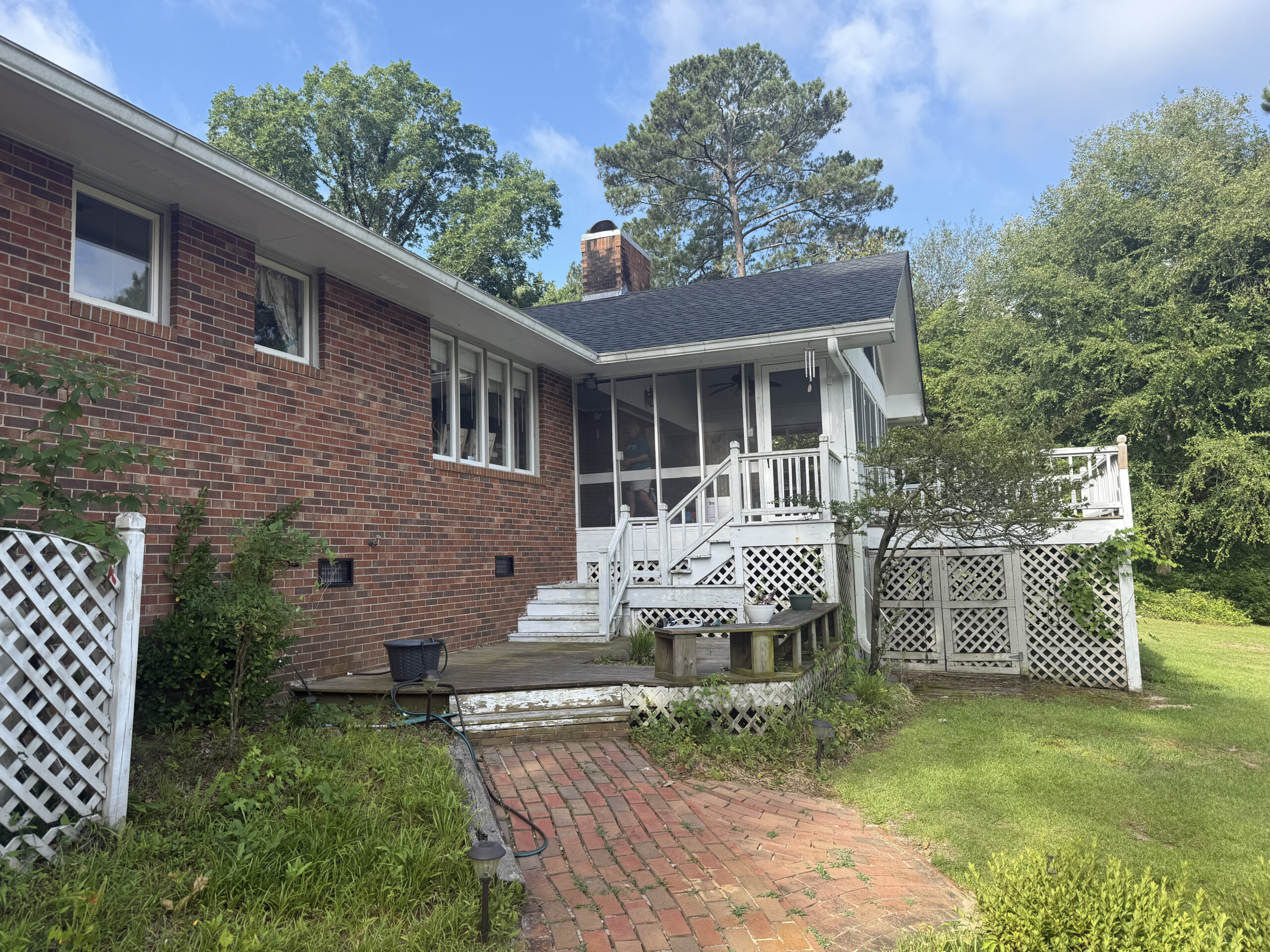 Worn wood deck and steps before resurfacing on a brick home in North Carolina
